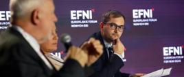 Wiceminister rozwoju i technologii Marek Niedużak siedzący w fotelu i trzymający w ręku kartki papieru podczas obrad EFNI'21 w Sopocie, obok siedzi eurodeputowany Jan Olbrycht