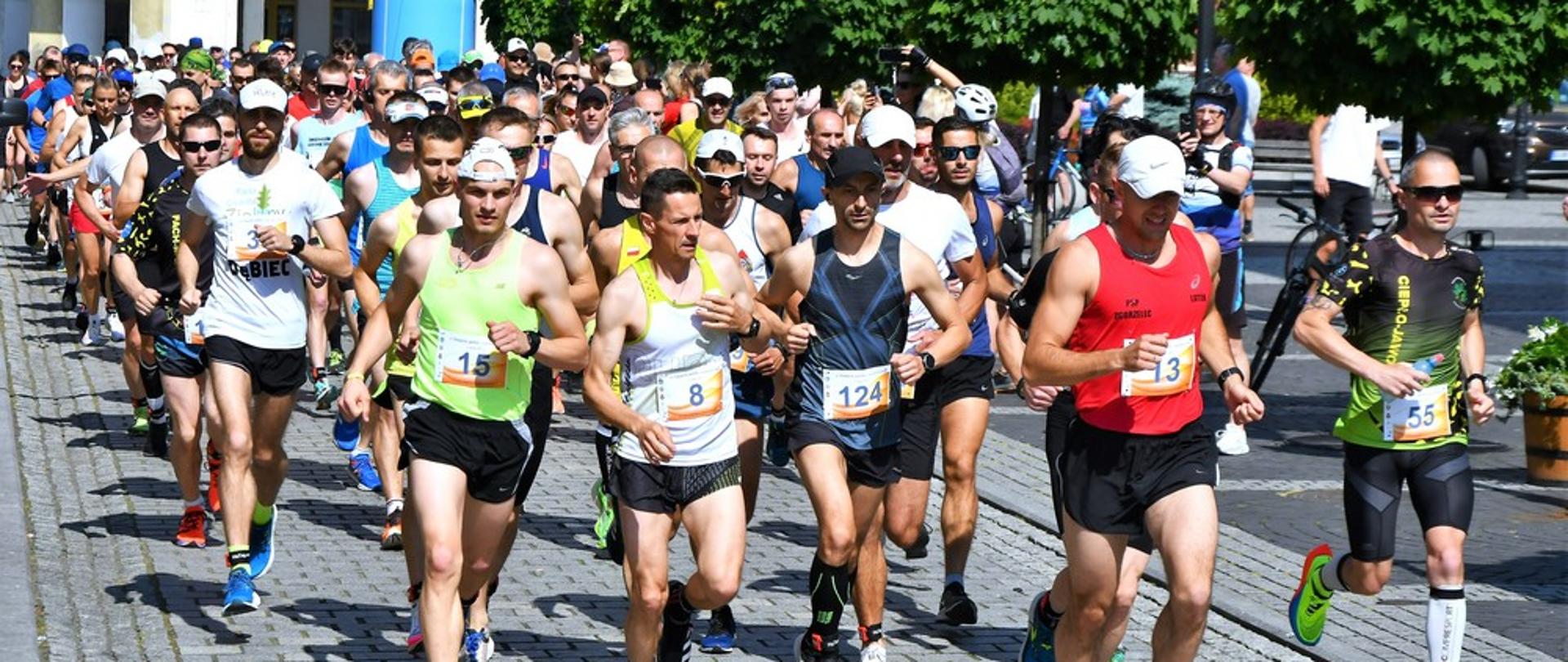 Obraz przedstawia zawodników startujących w Biegu Strażackim im. Adriana Kotkowskiego