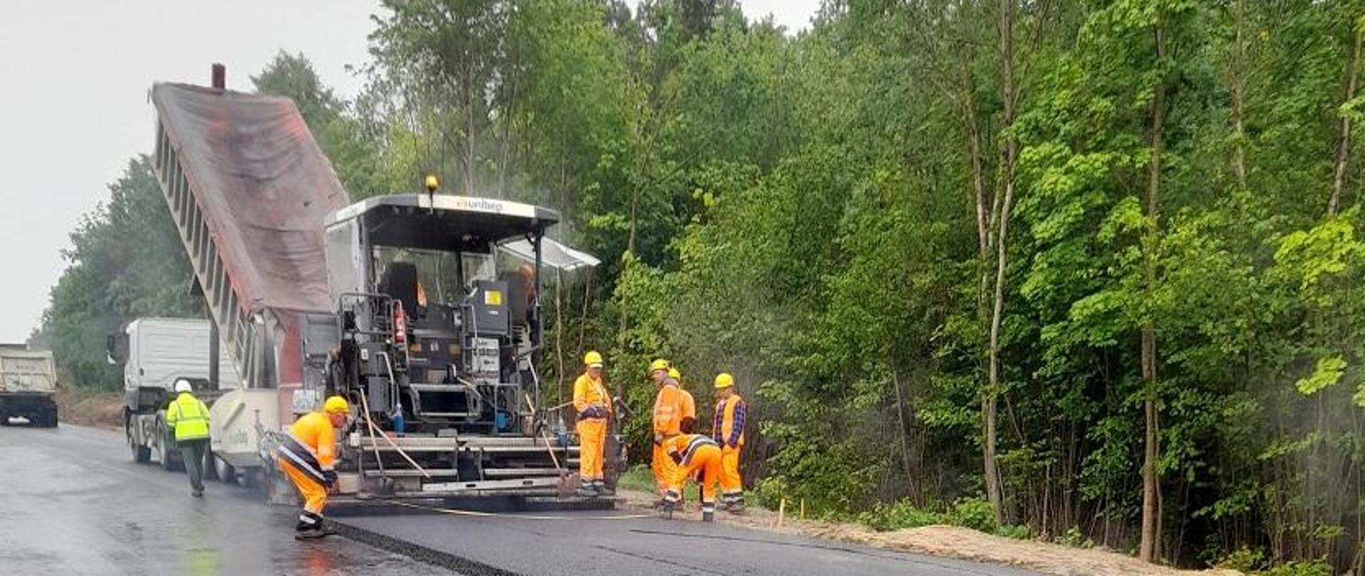 Układanie nowej nawierzchni na drodze - asfalt, maszyna i robotnicy w trakcie pracy 