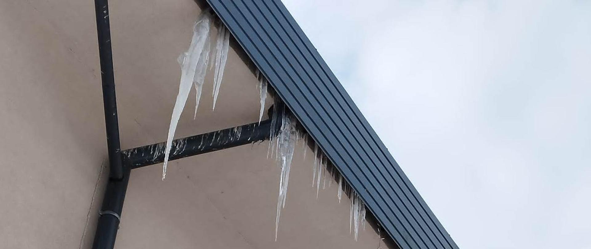 Z dachu budynku zwisają sople lodowe. 