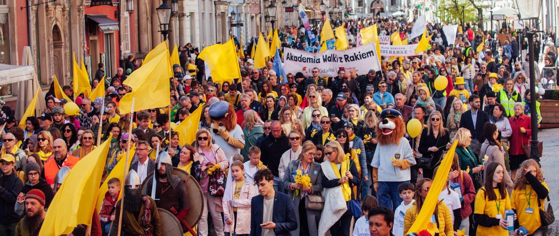 parada idzie przez Gdańsk, uczestnicy trzymają żonkile i transparenty