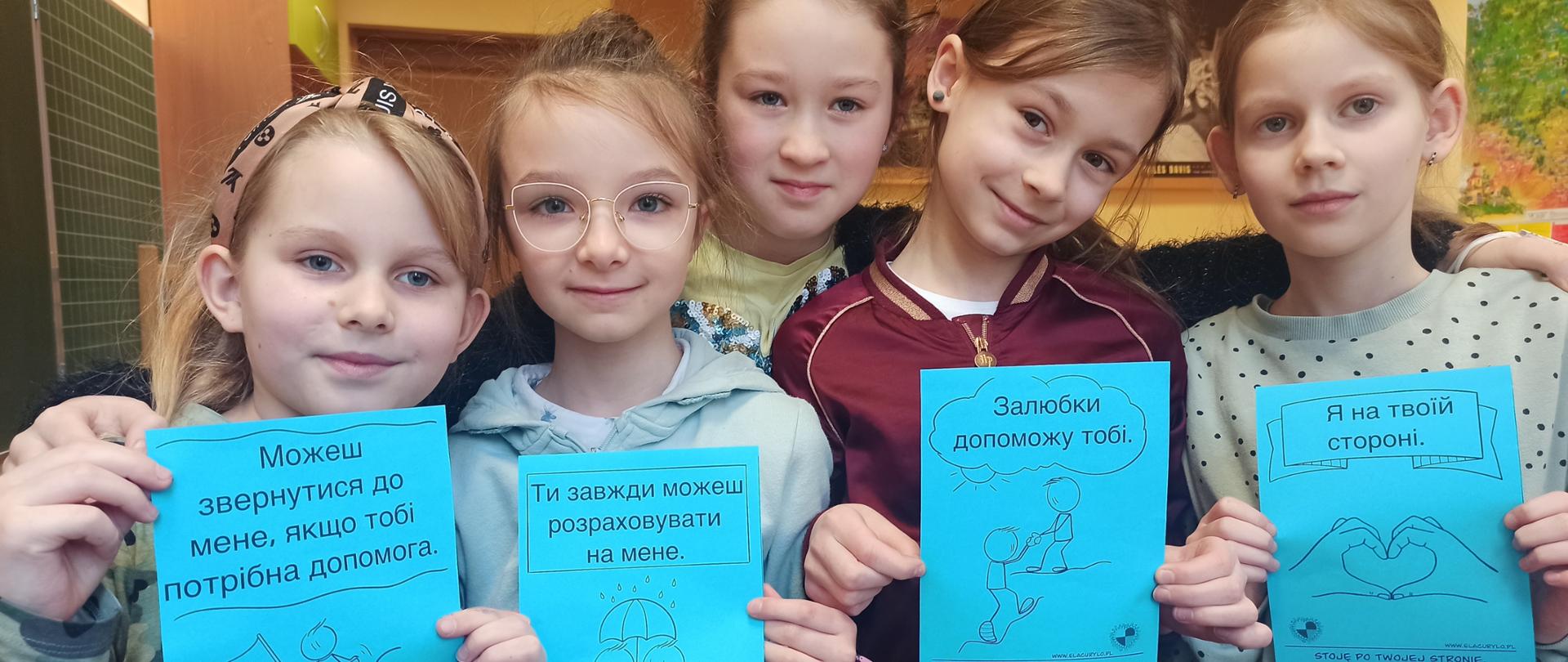 Uczniowie trzymają kartki z napisami otuchy dla obywateli Ukrainy