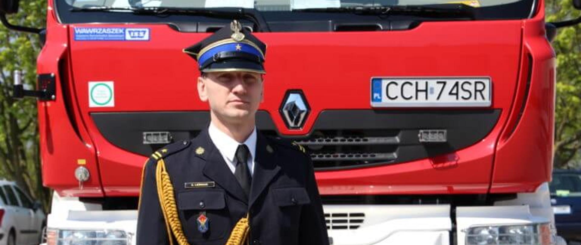 Na zdjęciu dyżurny stanowiska kierowania stoi przed samochodem bojowym. 