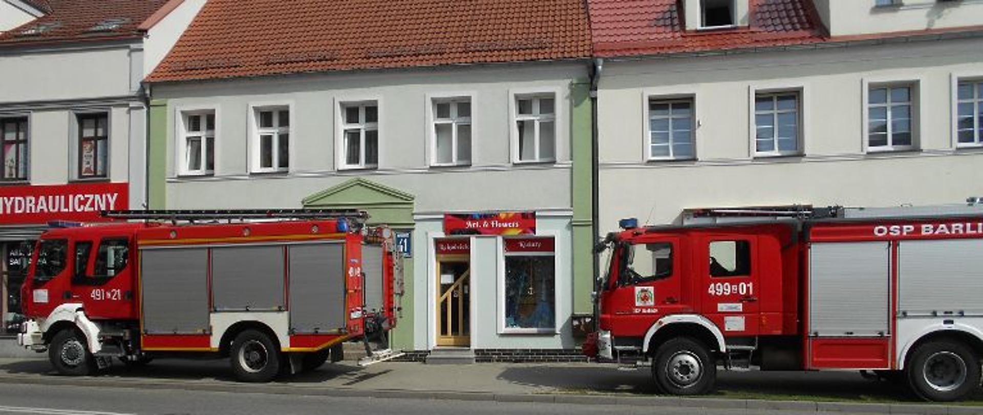 Na zdjęciu dwa pojazdy straży pożarnej na tle kamienic.