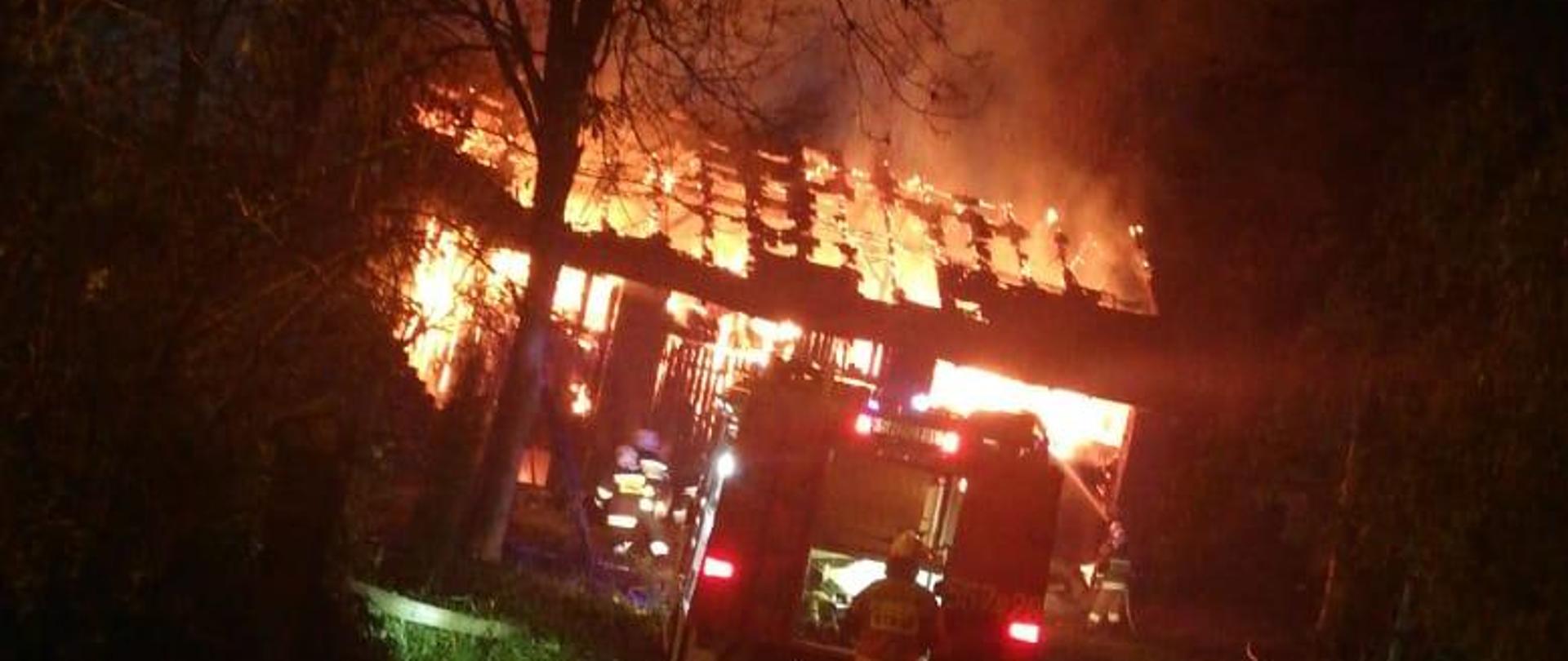 Zdjęcie przedstawia objętą ogniem stodołę oraz działania gaśnicze prowadzone przez strażaków