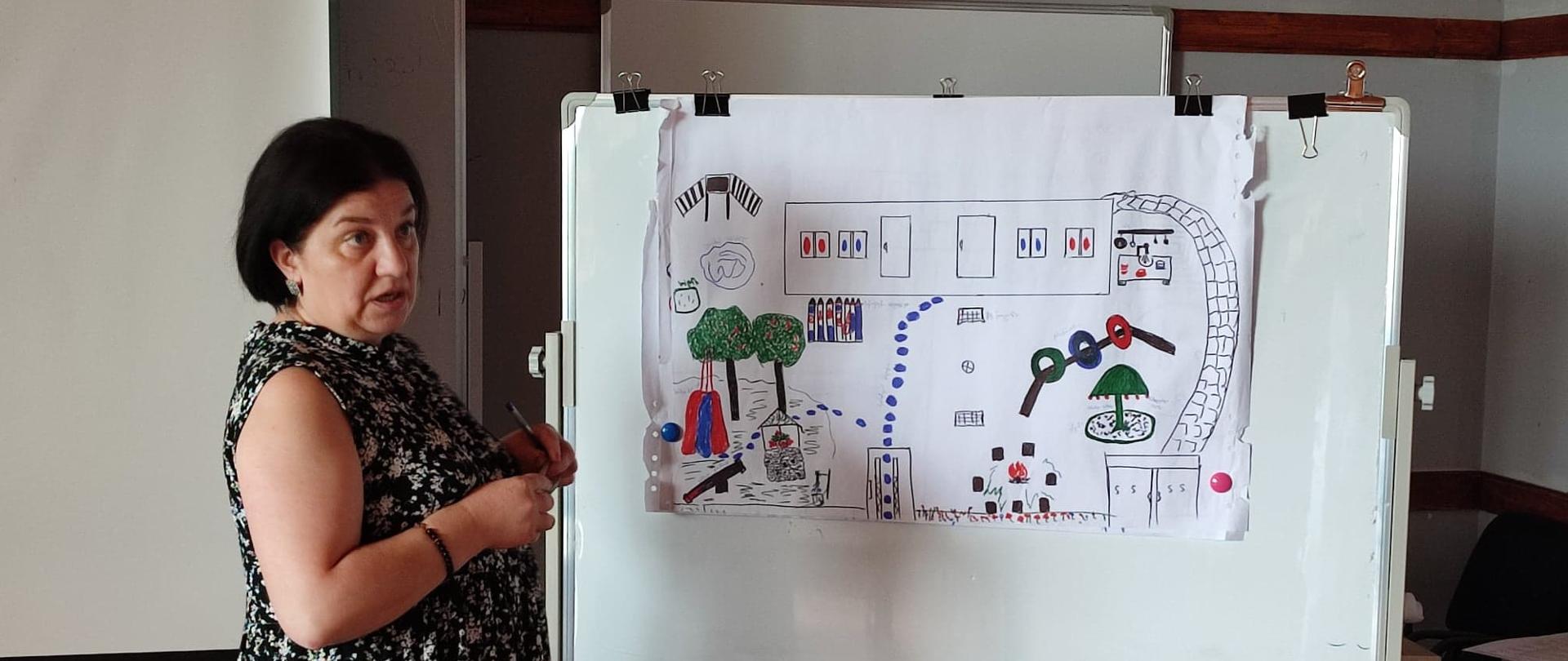 Kobieta przy tablicy z planem nowego placu zabaw