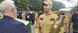 Zdjęcie przedstawia strażaka, który wygrał mistrzostwa i trzyma puchar w ręce, który wręczał wicestarosta. 