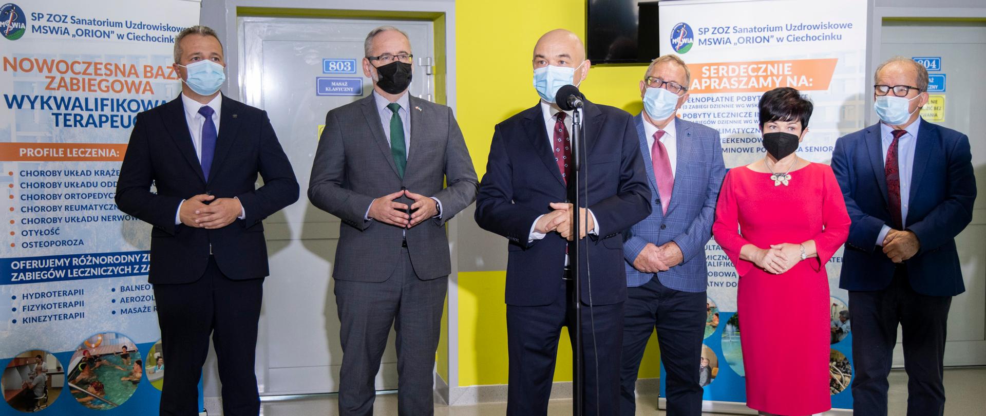 
Grupa ludzi w maseczka stojąca na holu
