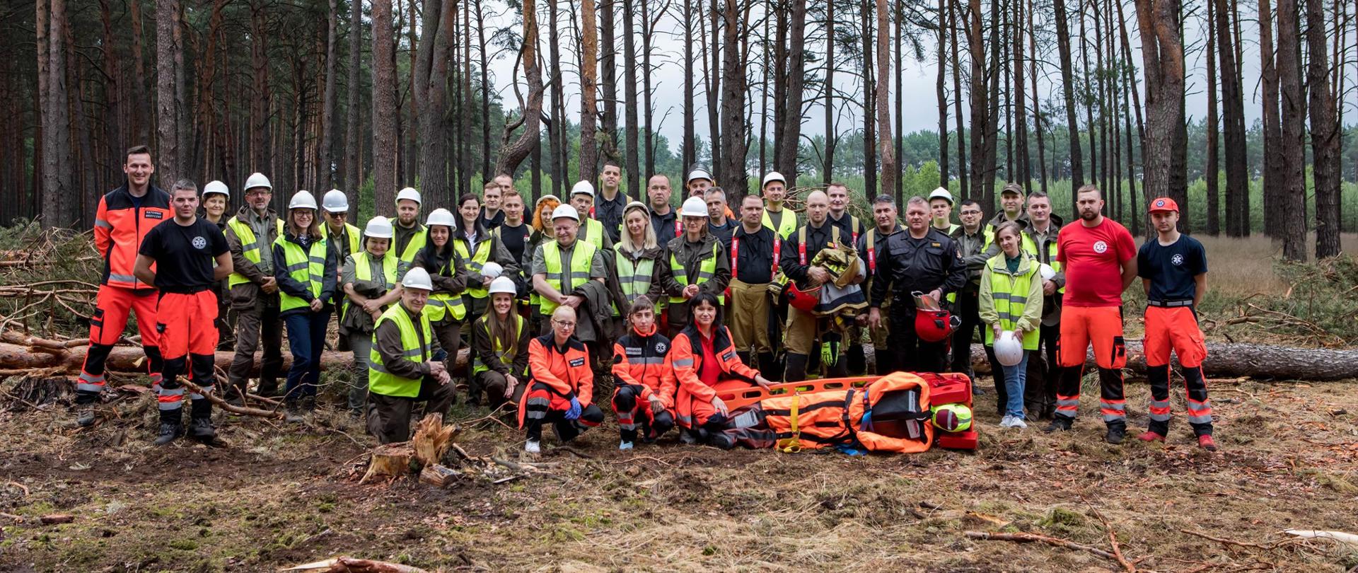 Jest to wspólne pamiątkowe zdjęcie wszystkich osób biorących udział w ćwiczeniach. Na zdjęciu widać strażaków, leśników oraz przedstawicieli Katedry Ratownictwa Medycznego Państwowej Uczelni Stanisława Staszica w Pile.