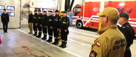 Zdjęcie przedstawia strażaków w trakcie uroczystego wręczania decyzji jubileuszowej.
W tle pomieszczenie garaży JRG.
