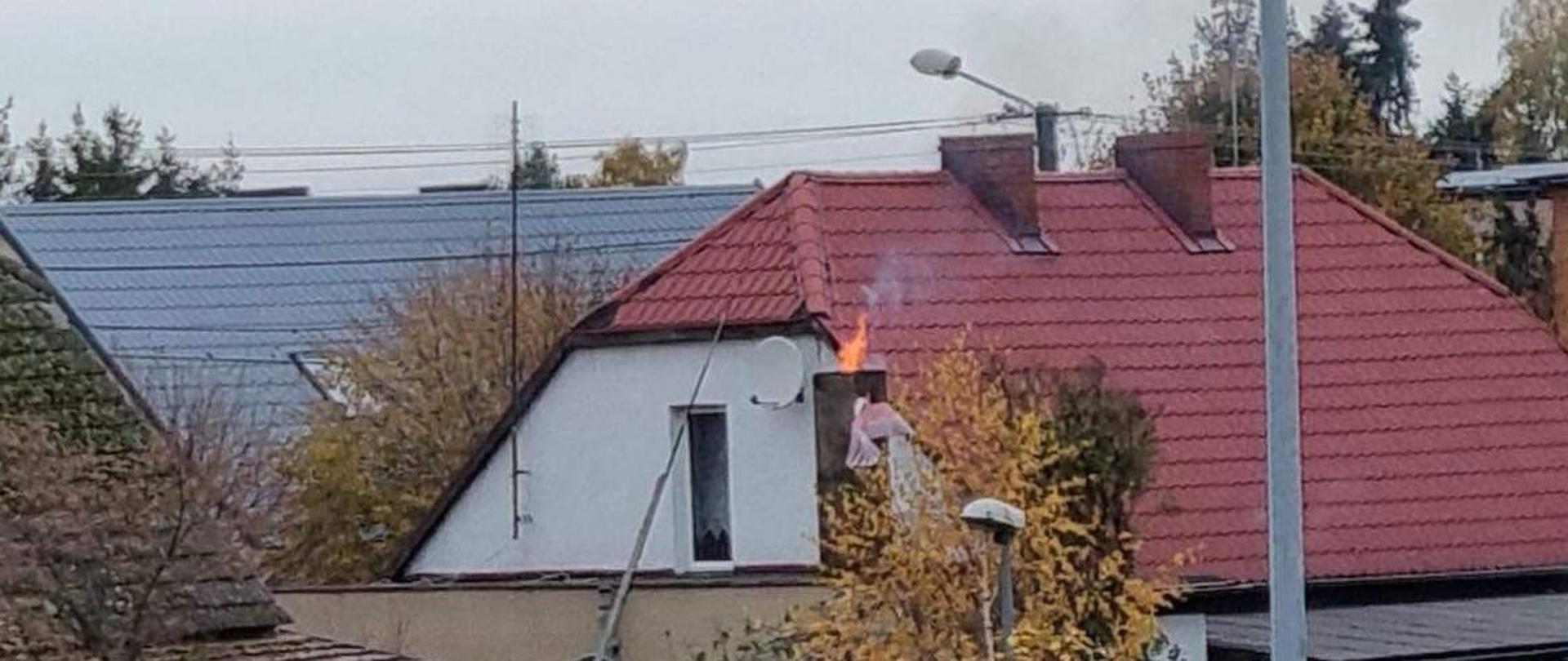 Ogień wydobywający się z komina budynku mieszkalnego
