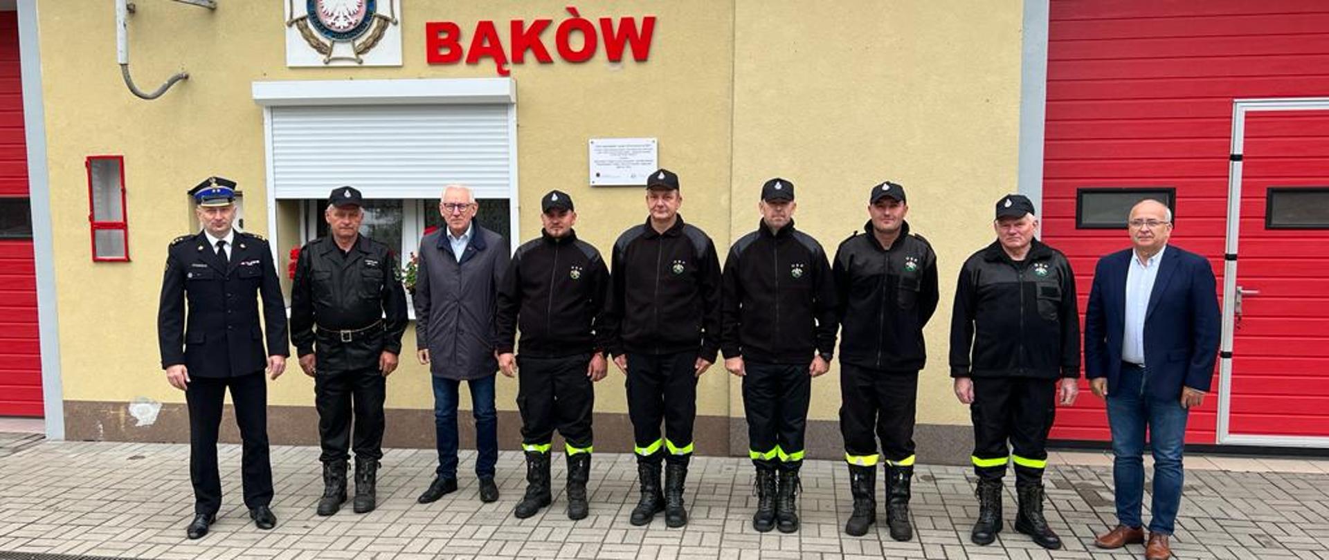 Wizyta Zastępcy Komendanta Wojewódzkiego PSP w jednostce OSP Bąków - zdjęcie przedstawia Z-cę Komendanta PSP w Opolu, władze samorządowe oraz druhów OSP przed budynkiem remizy
