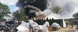 Zdjęcie przedstawia pożar składowiska odpadów, czarny, gęsty dym i płomienie