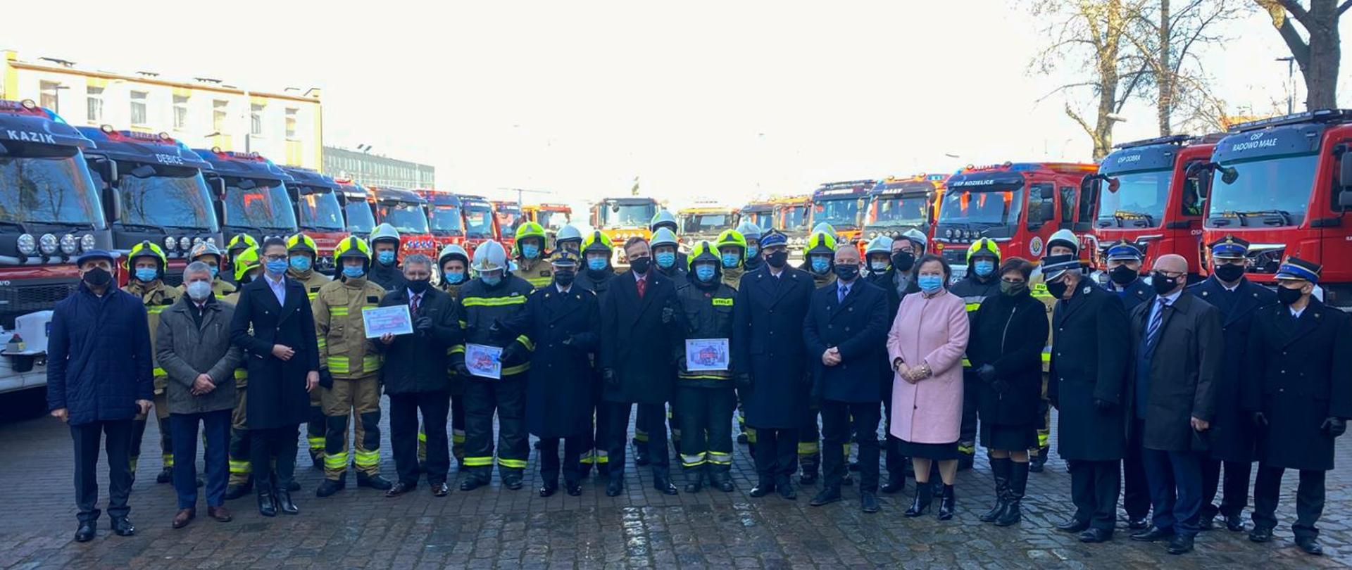 Zdjęcie grupowe na tle przekazywanych samochodów, wszyscy w maseczkach