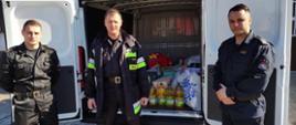 Zdjęcie przedstawia funkcjonariuszy Komendy Powiatowej PSP w Lwówku Śląskim stojących na tle samochodu, w którym znajdują się zakupione produkty spożywcze i środki higieniczne w ramach pomocy Ukrainie.
