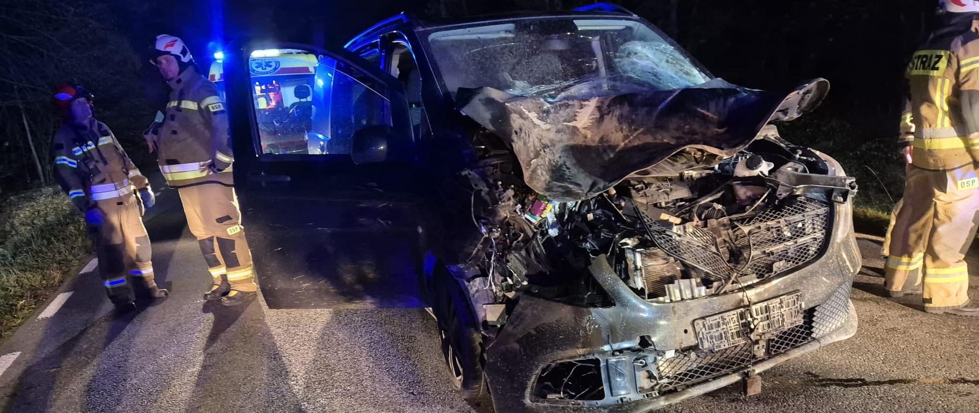 Na zdjęciu znajduje się wrak samochodu oraz strażacy w nomexach