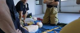 Założenia egzaminu praktycznego kończącego szkolenie podstawowe OSP. Strażacy ćwiczący udzielanie pierwszej pomocy przy wykorzystaniu fantomów szkoleniowych osoby dorosłej, dziecka i niemowlęcia. 