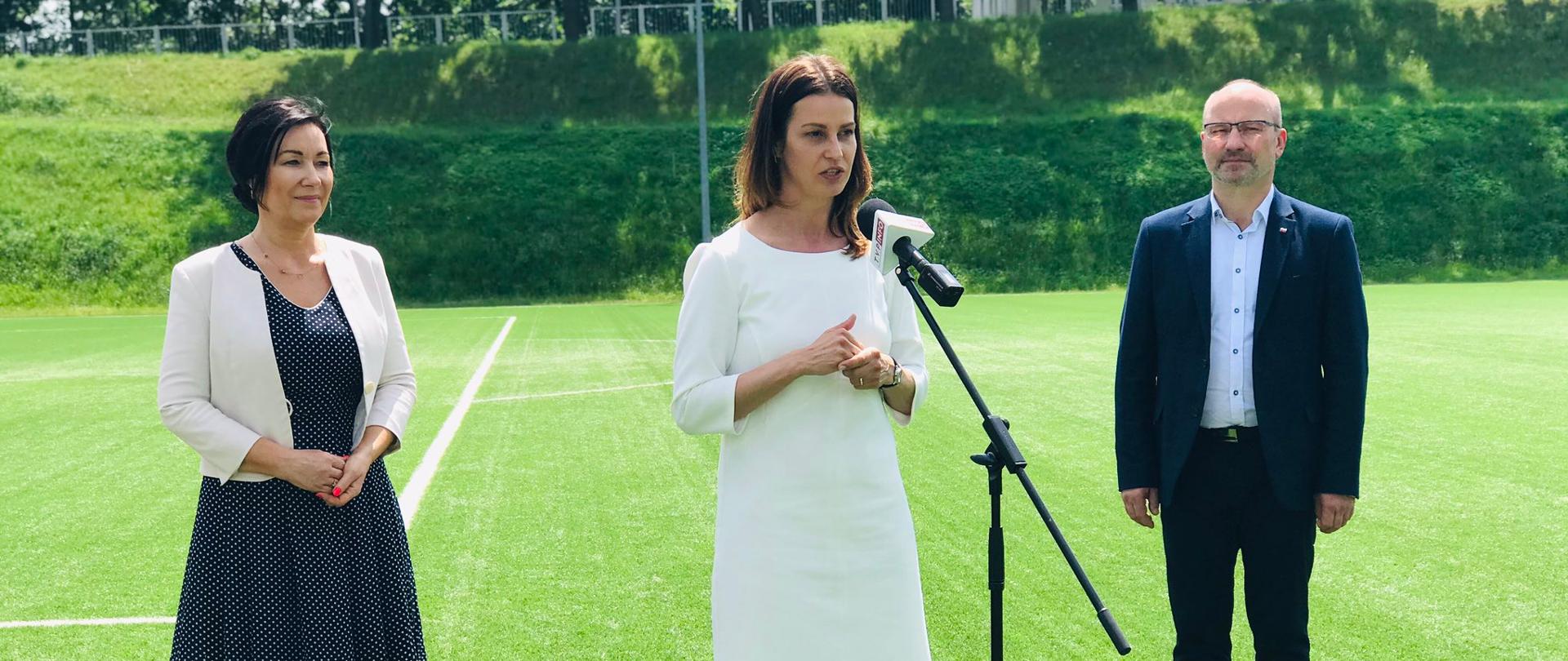 Danuta Dmowska-Andrzejuk przemawia do mikrofonu na boisku piłkarskim.
