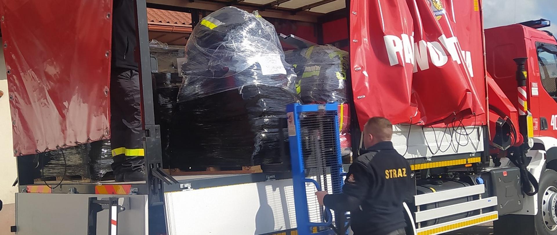 Strażacy ładują sprzęt na samochód kwatermistrzowski