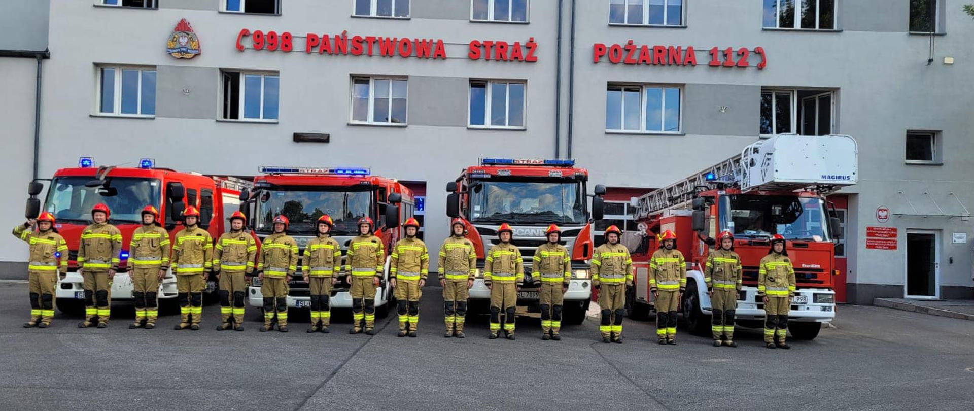 Na zdjęciu znajdują się strażacy z JRG 1 Ruda Śląska ustawieni w szeregu przed samochodami ratowniczo gaśniczymi, na tle jednostki ratowniczo gaśniczej.