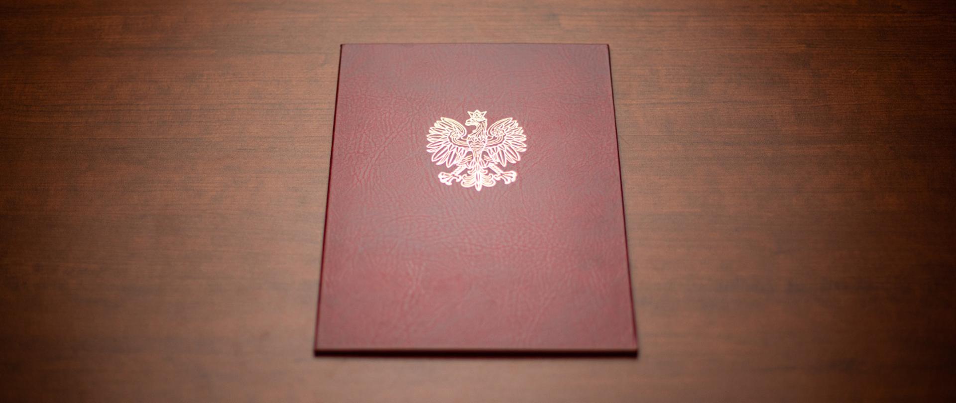Na zdjęciu widać twardą oprawę na dokumenty z wytłoczonym orłem z godła narodowego.