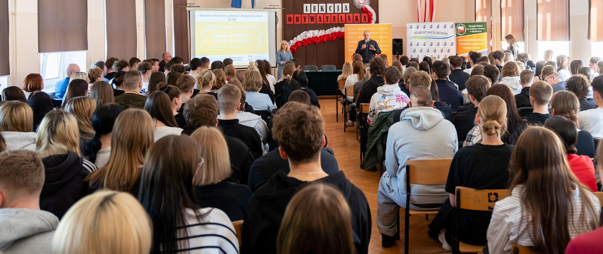 wojewoda prowadzi lekcję obywatelską w dużej, wypełnionej ludźmi sali