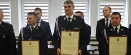 Strażacy w umundurowaniu z aktami włączenia do KSRG.