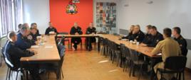 Strażący siedzą przy stole biorądz udział w naradzie.