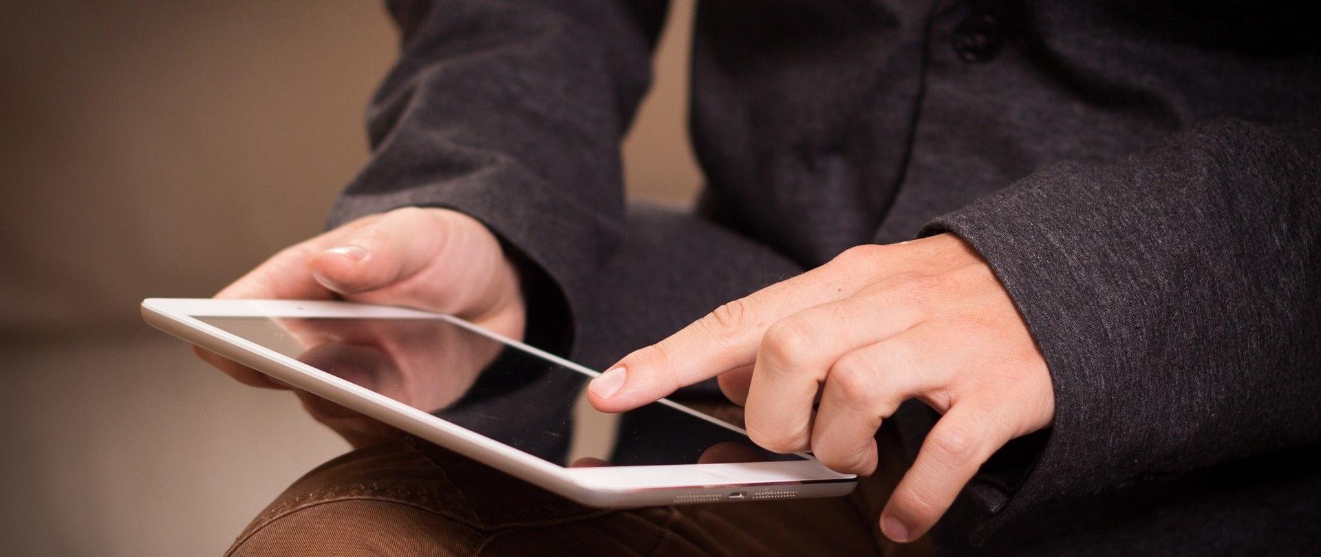 zdjęcie symbolizujące przedsiębiorczość - mężczyzna trzyma tablet na kolanach