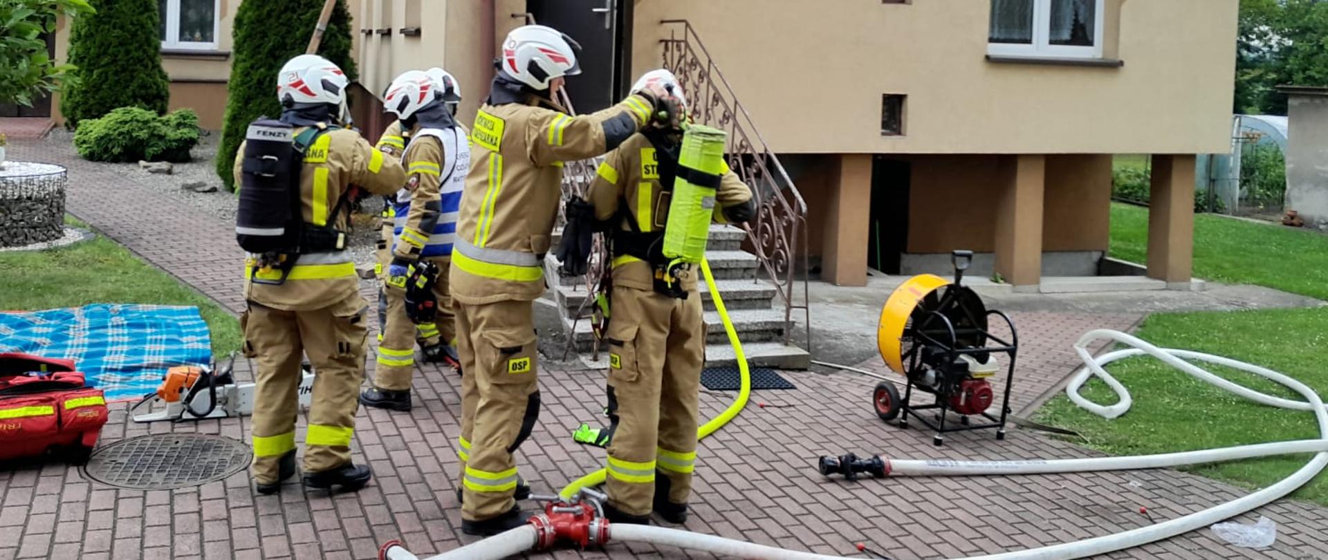 Na zdjęciu strażacy przed budynkiem prowadzą działania ratowniczo - gaśnicze
