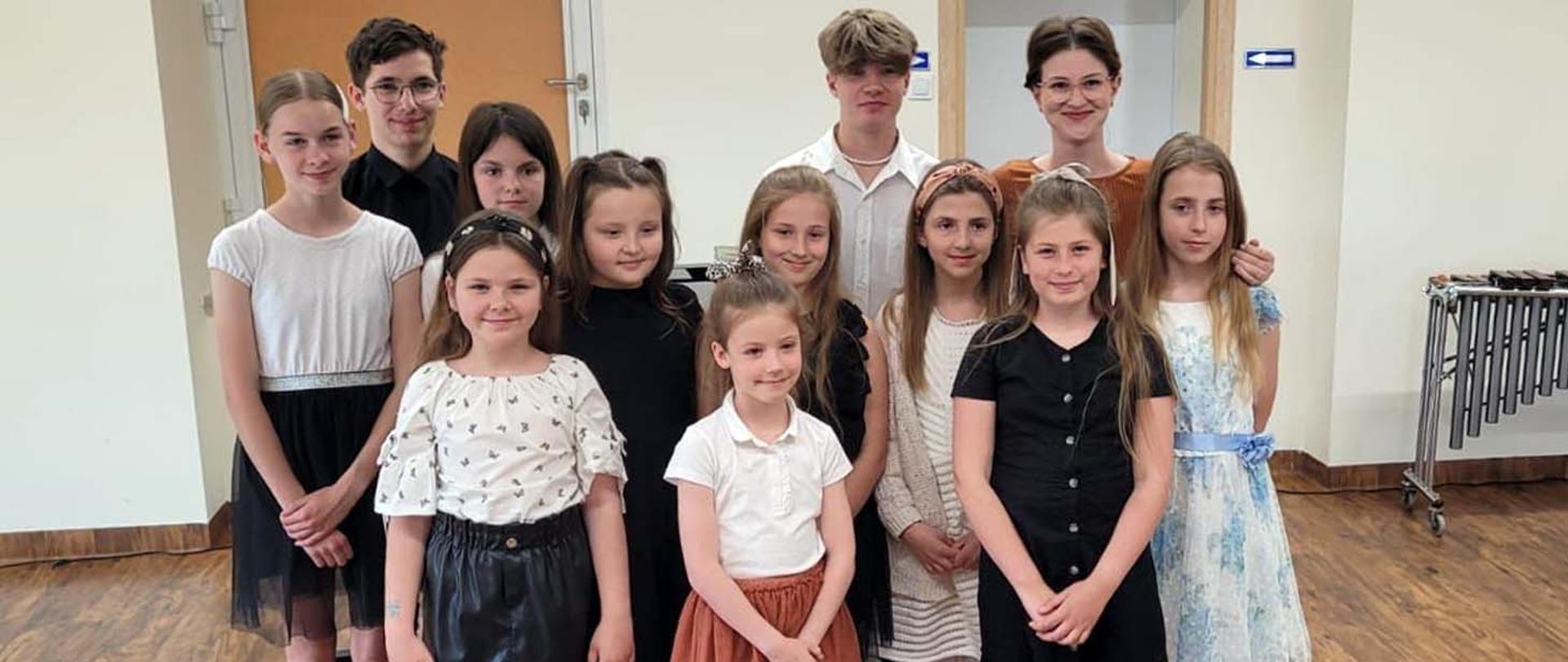 11 uczniów, dziewczynki i chłopcy pozują do zdjęcia wraz ze swoją nauczycielką.