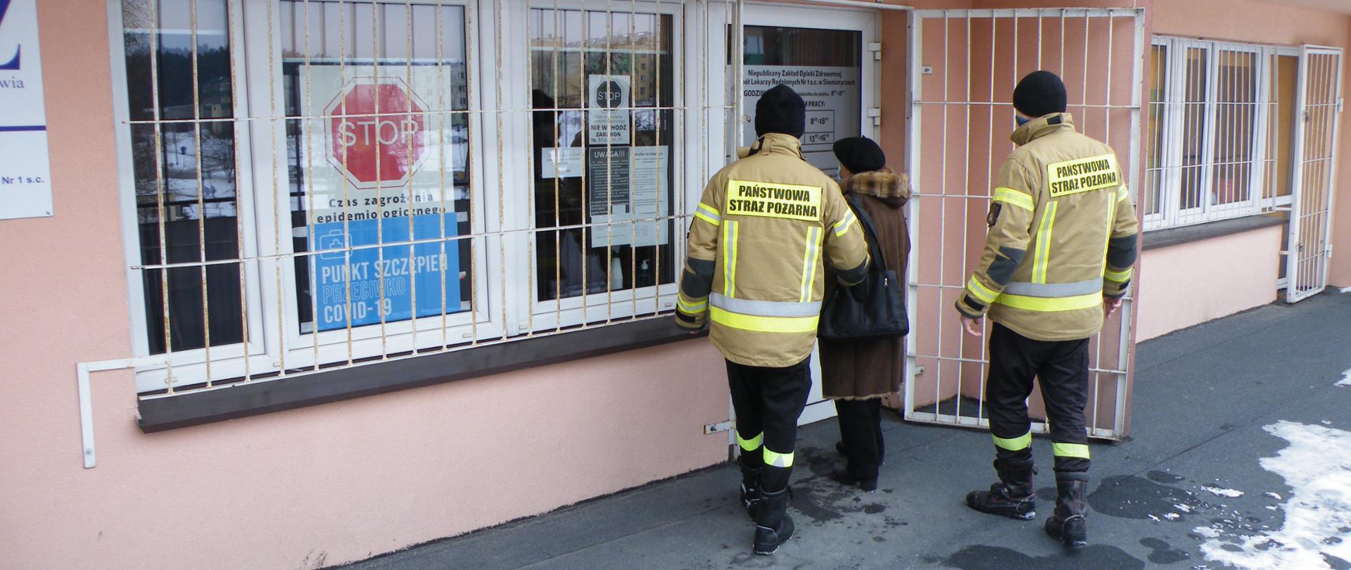 Strażacy doprowadzają osobę starszą do punktu szczepień