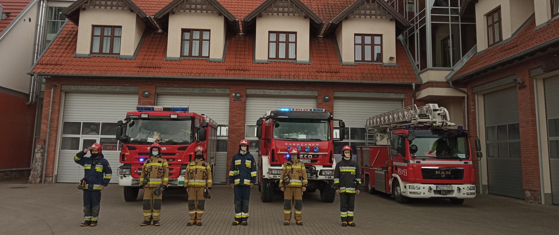 Zdjęcie przedstawia gołdapskich strażaków, którzy uczcili pamięć zmarłego Policjanta poprzez oddanie honoru oraz włączenie sygnałów świetlnych i dźwiękowych w pojazdach.
