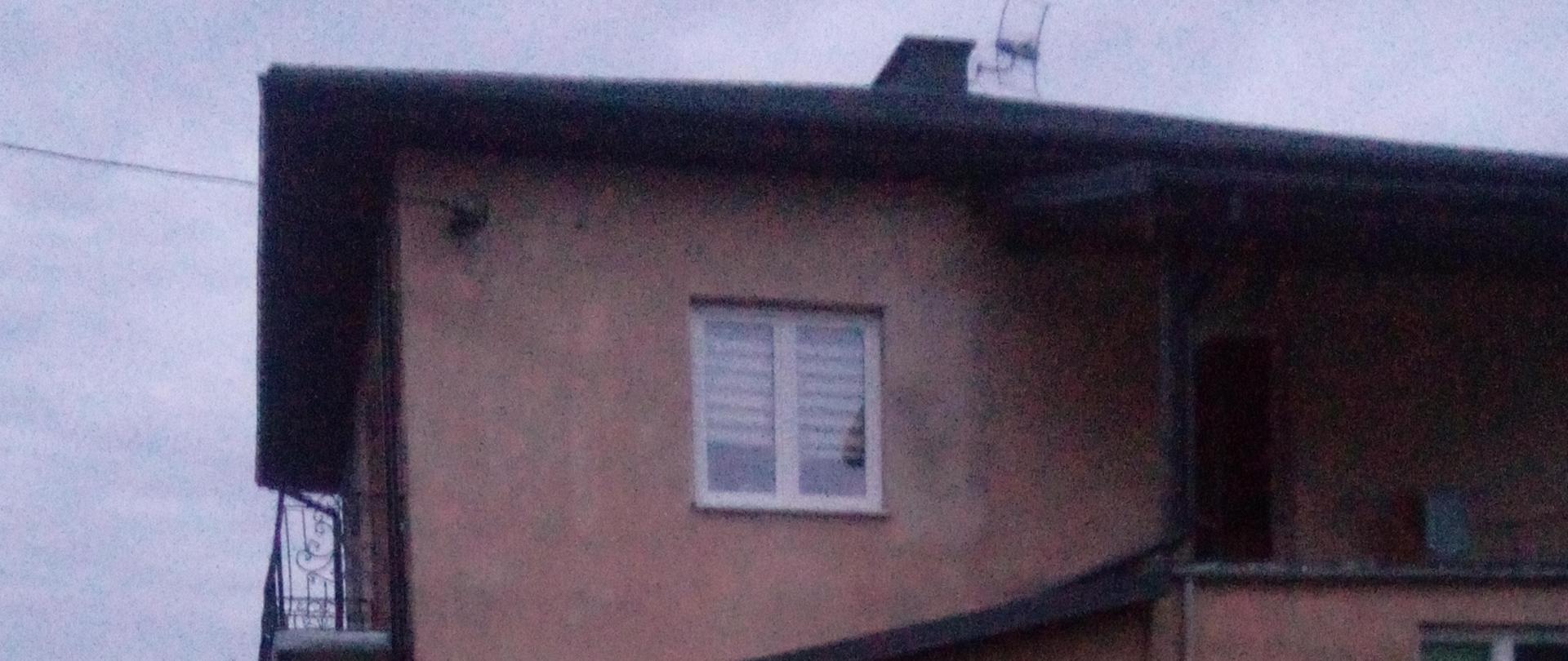 Zdjęcie przedstawia 11 kg butlę propan butan otoczoną przez kurtyny wodne. W tle wydać budynek mieszkalny