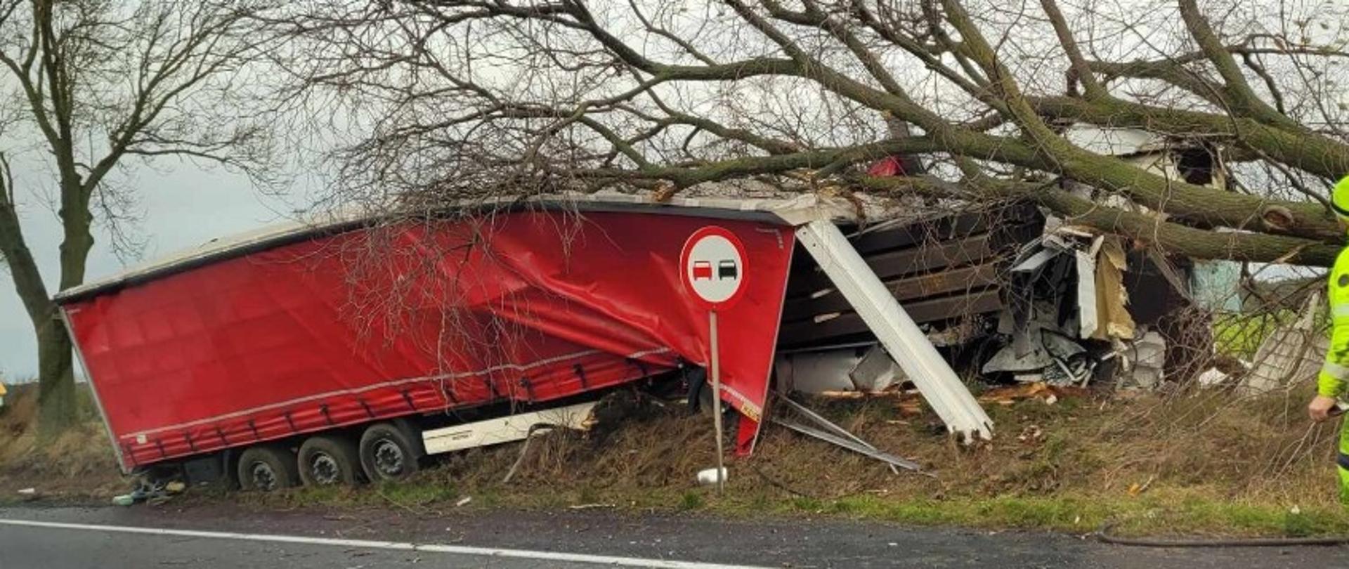 Samochód przy drzewie, za nim mocno uszkodzona naczepa w rowie