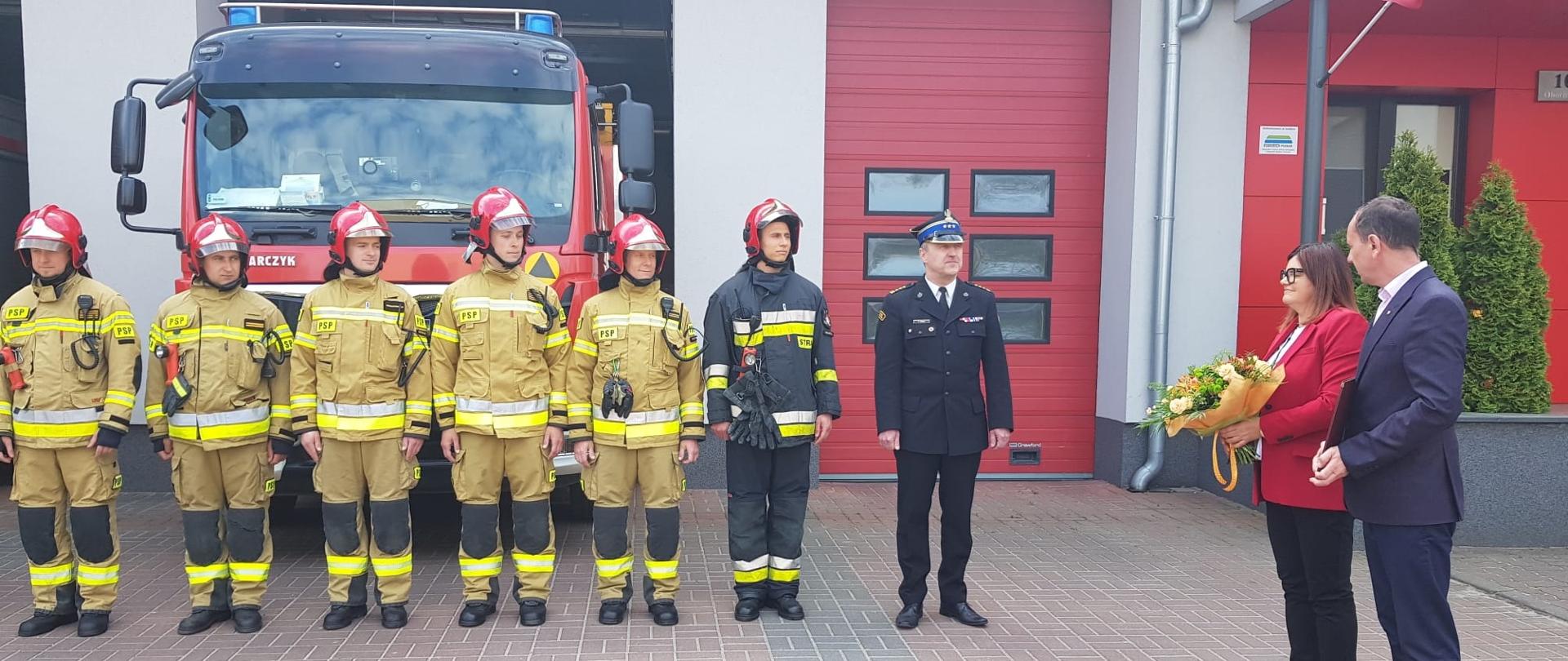 Widać kliku strażaków na tle samochodu, po prawej starosta powiatu szamotulskiego