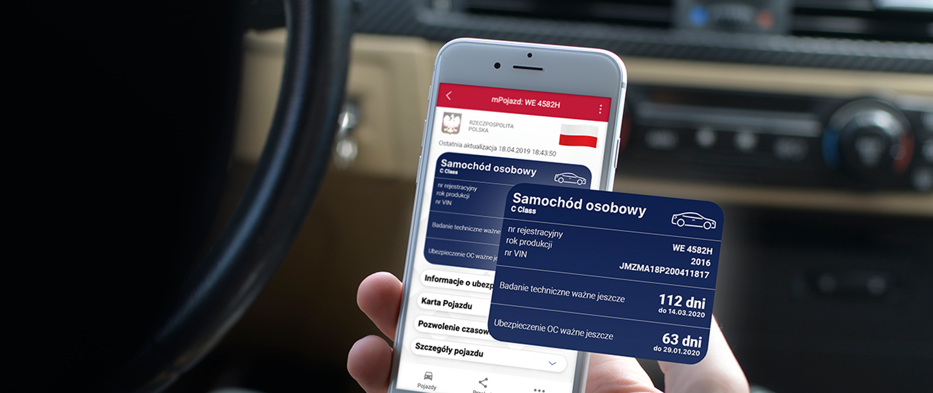 Wnętrze samochodu. Kierowca trzymający w dłoni smartfona, w którym wyświetla się aplikacja mObywatel.