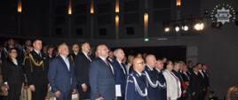 Uczestnicy uroczystości z okazji dnia policji stoją podczas odgrywania hymnu