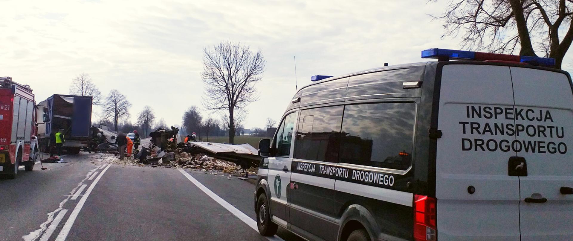 Inspektorzy świętokrzyskiej Inspekcji Transportu Drogowego na miejscu śmiertelnego wypadku. Na pierwszym planie furgon ITD. W oddali po lewej wóz strażacki, w centrum dwie roztrzaskane ciężarówki.