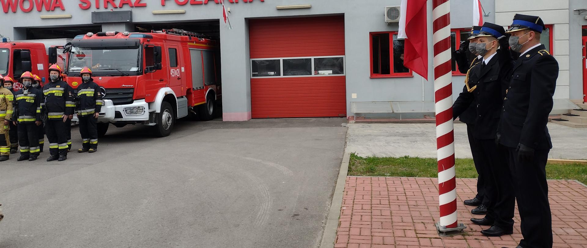 Zdjęcie przedstawia funkcjonariuszy oddających honory podczas podnoszenia flagi Rzeczpospolitej Polskiej