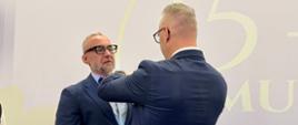 Mężczyzna w garniturze, wojewoda, przypina odznaczenie 
