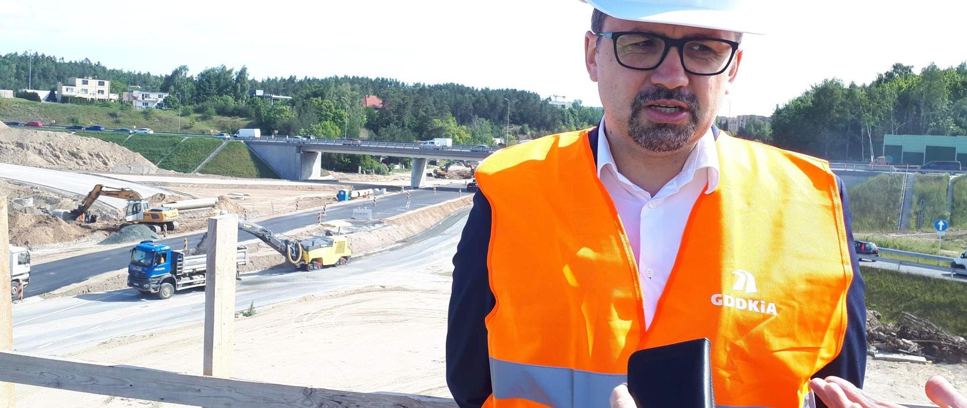 wiceminister Marcin Horała odpowiada dziennikarzowi, za nim budowa drogi