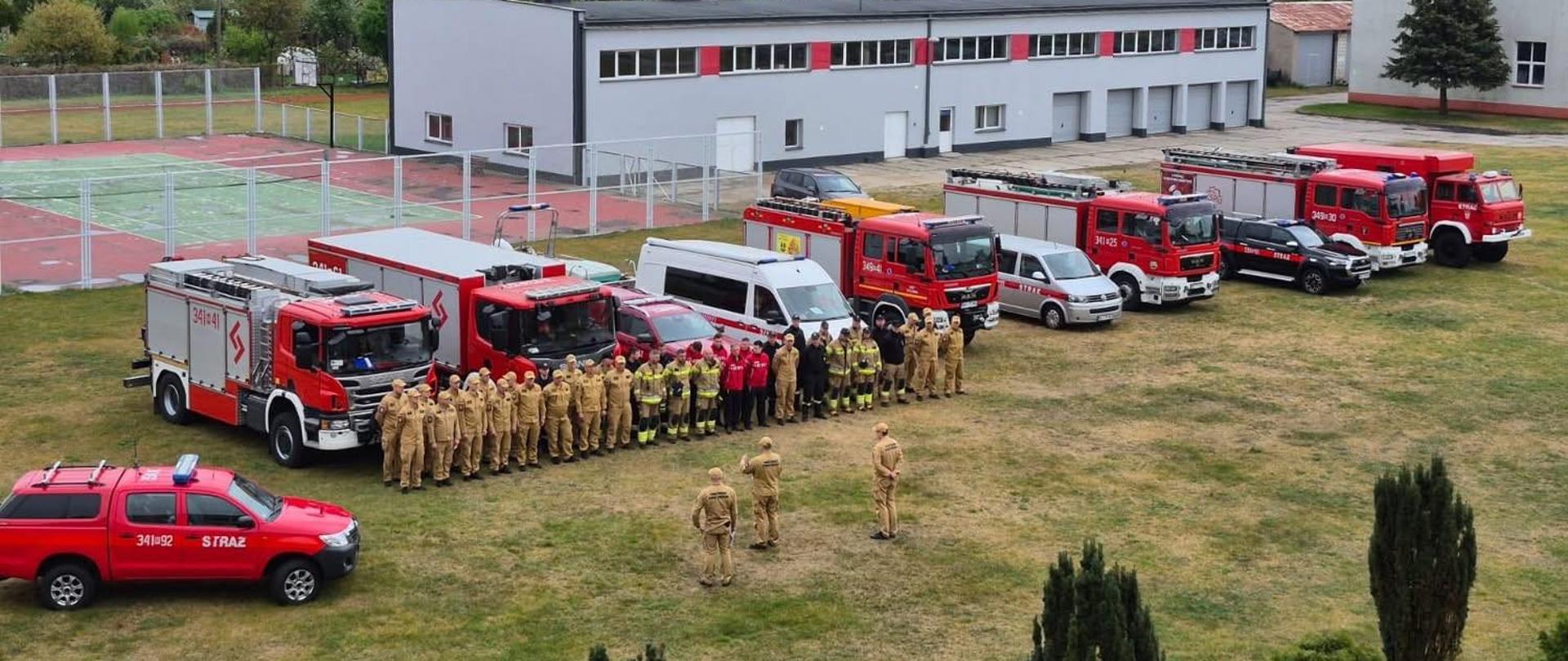 Plan szeroki na strażaków i wozy strażackie.
