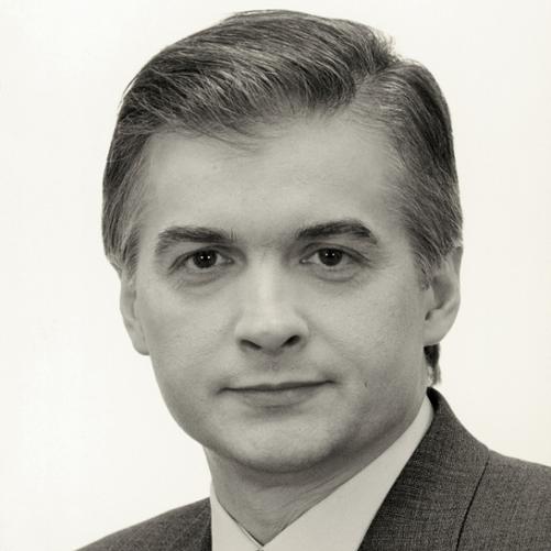 Włodzimierz Cimoszewicz czarno - biały portret mężczyzny, siwiejące włosy, szara marynarka w paski, wzorzysty krawat, biała koszula.