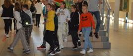Ćwiczenia ewakuacyjne. Szkoła Podstawowa w Sierakowie. Uczniowie szkoły pod nadzorem nauczyciela ewakuują się klatką schodową po tym jak ogłoszony został alarm. Chłopcy i dziewczęta mają na sobie kolorową odzież. Kilku chłopców trzyma się poręczy.