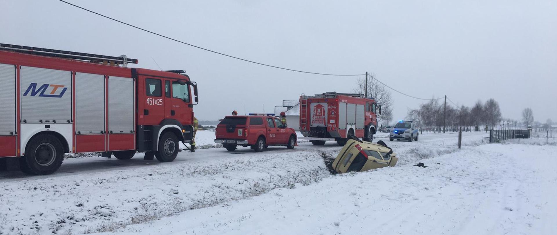 widoczne miejsce zdarzenia, uszkodzony pojazd oraz służby ratownicze działające na miejscu.