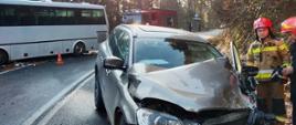 Rozbity samochód osobowy i autobus na drodze.