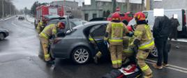 dwa samochody biorące udział w wypadku na środku drogi dookoła strażacy