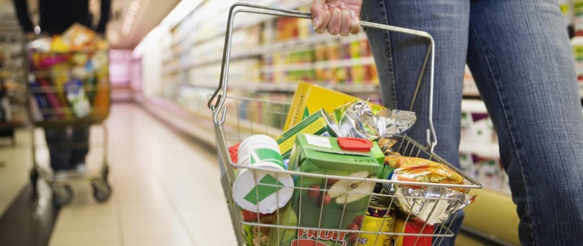 koszyk metalowy na zakupy wypełniony produktami spożywczymi w opakowaniach