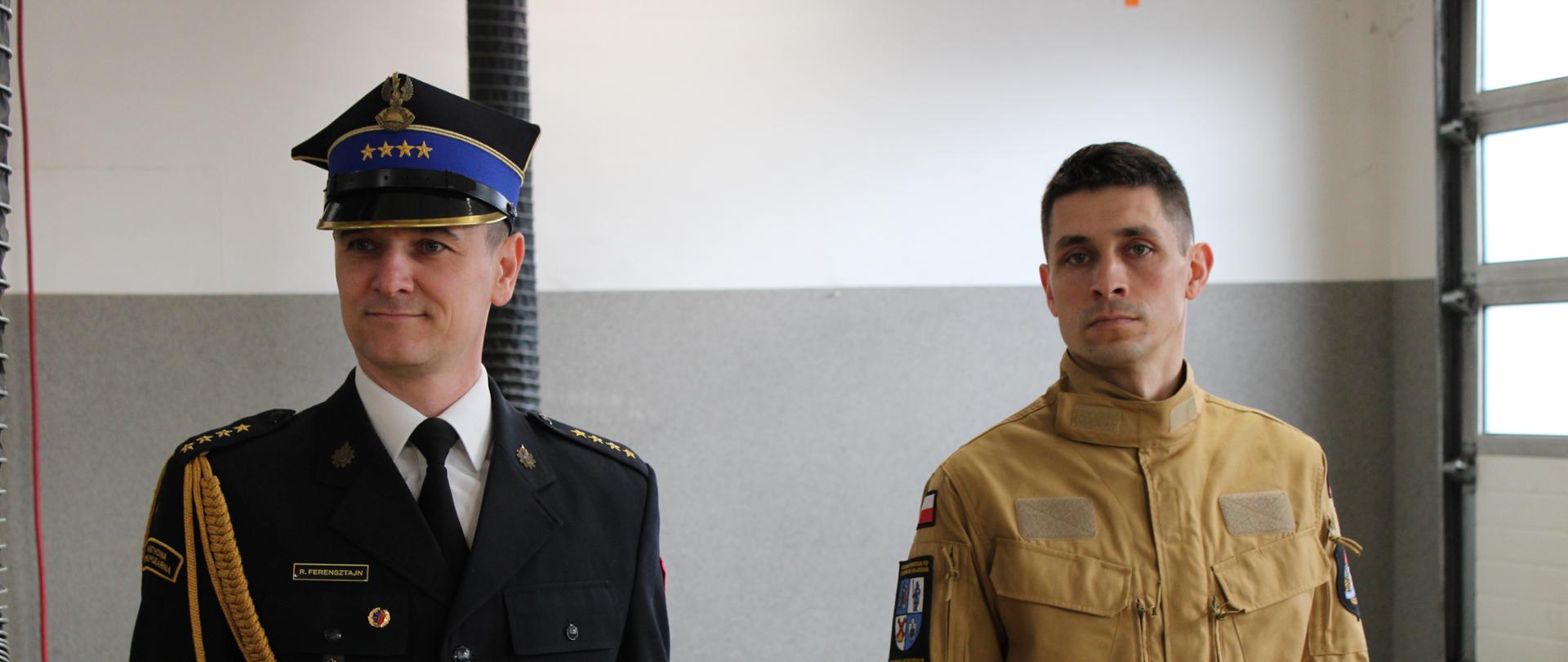 dwóch funkcjonariuszy państwowej straży pożarnej, jeden z nich ma na sobie mundur wyjściowy, drugi ubrany jest w mundur służbowy, zdjęcie wykonane w garażu komendy powiatowej państwowej straży pożarnej w sępólnie krajeńskim